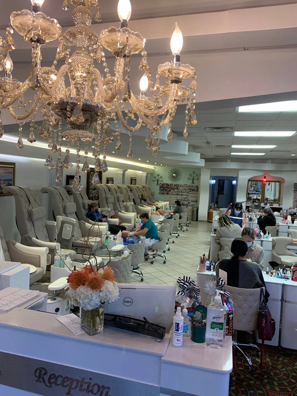A nail technician working with a seated client at Solar Nails.