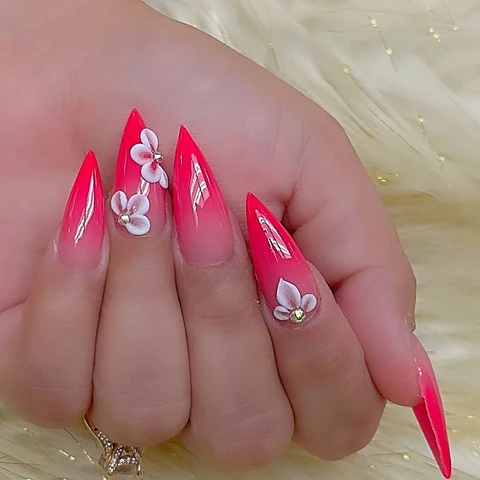 Bright pink pointed nails with raised white flowers.