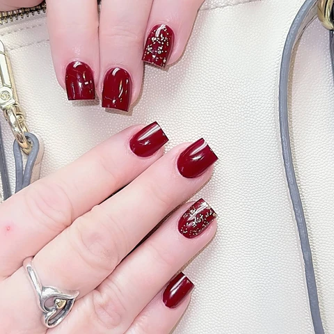 Glossy burgundy nails with sparkling accent nails.